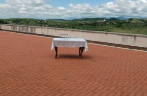 Mit Gläsern gedeckter Tisch auf einer riesigen Terasse mit weitem Blick auf Hügel und Wolken